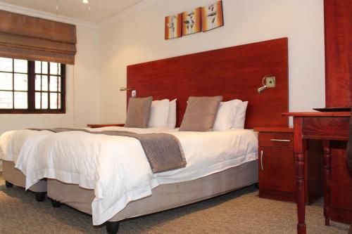 a large bedroom with a large bed and a desk at Sir Roys Guest House in Port Elizabeth
