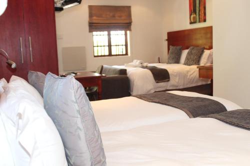 a hotel room with three beds and a desk at Sir Roys Guest House in Port Elizabeth