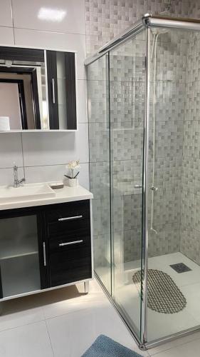 La salle de bains est pourvue d'une douche en verre et d'un lavabo. dans l'établissement Summer Beach Paiquere, à Araranguá