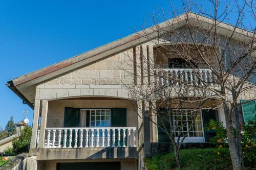 a brick house with a balcony and a tree at Casa da barragem - Ninho das Águias in Venda Nova