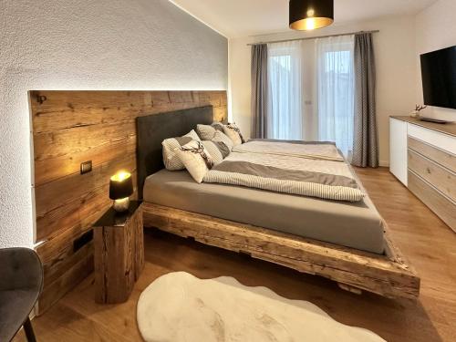 a bedroom with a large bed with a wooden headboard at Ferienwohnung BERGSEERUHE - Allgäu - Wandern - Relaxen in Sulzberg