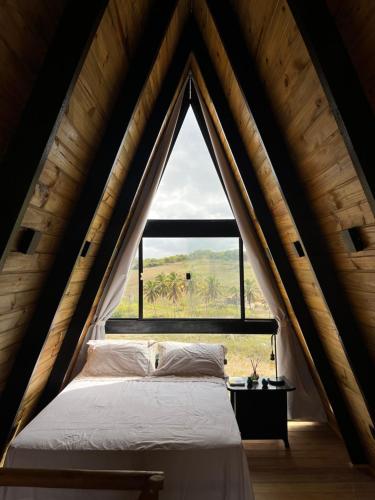 Cama en habitación con ventana grande en Cabana Estrelas da Colina, en Serra de São Bento