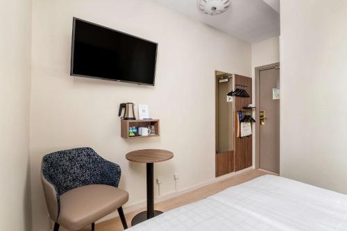 a room with a bed and a chair and a television at Best Western Hotel Karlaplan in Stockholm