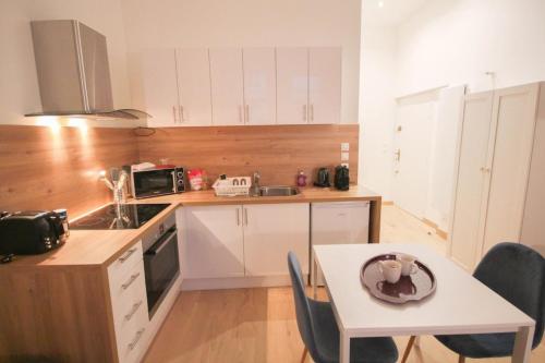 une cuisine avec des placards blancs et une table avec une plaque de cuisson. dans l'établissement Lille Centre - Superb equipped studio!, à Lille