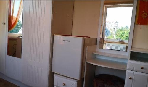 a kitchen with a refrigerator and a window at Kambario nuoma su bendru vonios kambariu in Kaunas