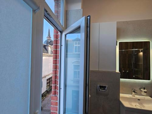 a bathroom with a sink and a door to a window at Main Street Apartments in Sopot