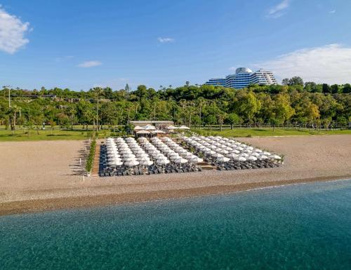 uma fila de mesas com guarda-sóis na praia em Rixos Downtown Antalya - The Land Of Legends Access em Antália