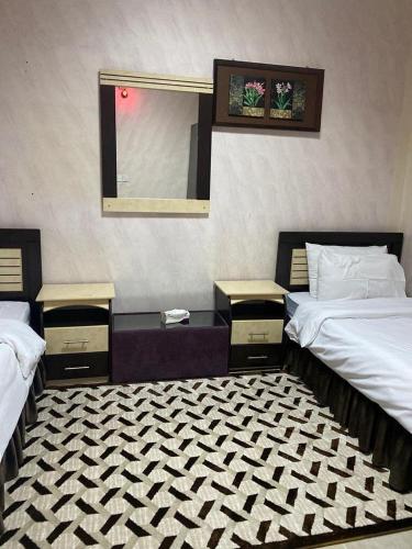 a hotel room with two beds and a mirror at دار السلام للشقق المخدومة الجوف دومة الجندل in Dawmat al Jandal
