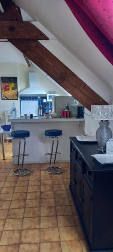 uma cozinha com dois bancos de bar azuis num quarto em L'ABRI em May-sur-Orne