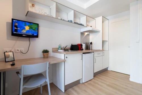 Il comprend une cuisine avec un bureau et une télévision murale. dans l'établissement Lille Hypercentre - Nice equipped studio, à Lille