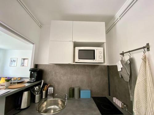 a small kitchen with a sink and a microwave at LE COSY studio proche PARIS avec parking & terrasse in Courcouronnes