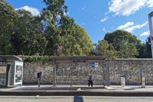 a woman is standing at a bus stop at INZO in Montpellier