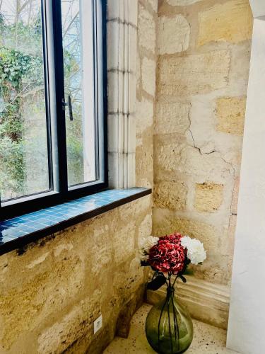 un vase rempli de fleurs assis à côté d'une fenêtre dans l'établissement The Hidden Gem Of Bordeaux, à Lormont