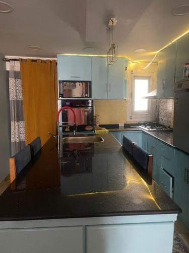 a kitchen with blue cabinets and a black counter top at Fekra in Luxor
