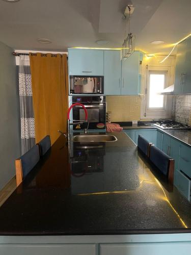 a kitchen with a black counter top and blue cabinets at Fekra in Luxor