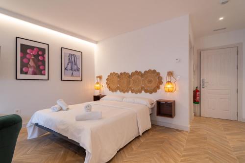 a white bedroom with a large bed and a tv at Edificio Correos 4 in Valladolid
