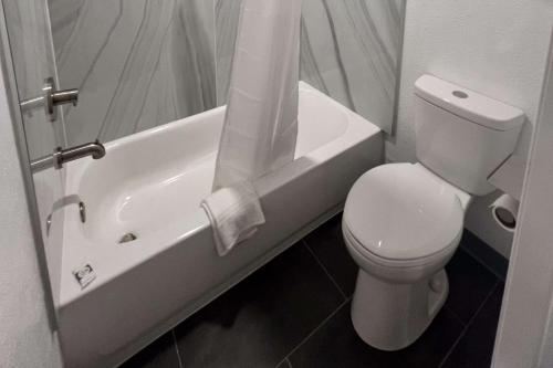ein weißes Bad mit einem WC und einer Badewanne in der Unterkunft Rodeway Inn in Mineola