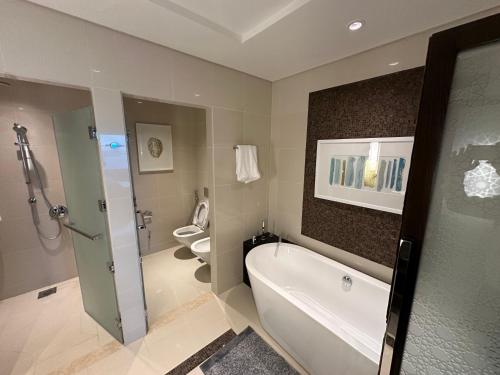 La salle de bains est pourvue d'une baignoire et de 2 toilettes. dans l'établissement Fairmont Marina Abu Dhabi, à Abu Dhabi