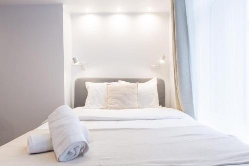 1 dormitorio con 1 cama con sábanas y almohadas blancas en Old Lille - studio ideally located !, en Lille