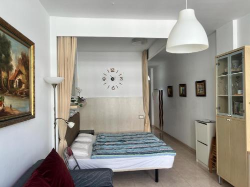 1 dormitorio con 1 cama y reloj en la pared en Edificio Playa, en Las Palmas de Gran Canaria