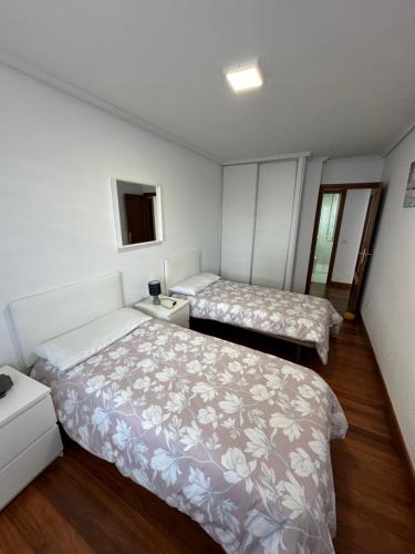 two beds in a small room with white walls at El Rincón del Faro - Parking incluido in San Vicente de la Barquera