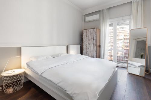 um quarto branco com uma cama grande e uma janela em #Alice by halu! Apartments em Tessalônica
