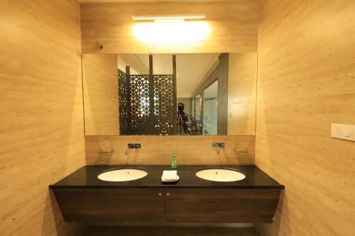 a bathroom with two sinks and a large mirror at The Byke Suraj Club, Junagadh in Junagadh