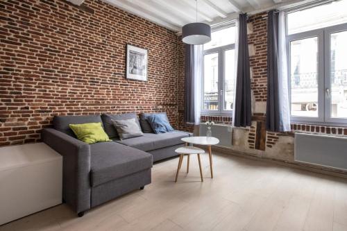 un soggiorno con divano e muro di mattoni di Old Town - Superb apartment in rue Esquermoise ! a Lille