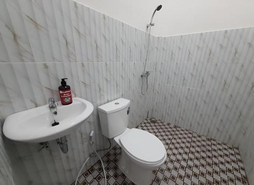 y baño con aseo blanco y lavamanos. en OYO 93306 Homestay Permana Supadio Airport, en Pontianak