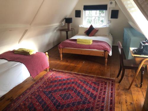 Schlafzimmer mit einem Bett, einem Tisch und einem Fenster in der Unterkunft Beautiful 18th Century Old Rectory with river in Norwich
