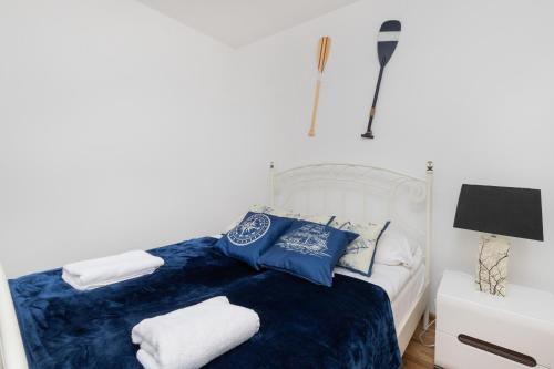 1 dormitorio con 1 cama blanca con sábanas y almohadas azules en Batorego 7 Apartament with Terrace & Parking Downtown Gdynia by Renters, en Gdynia