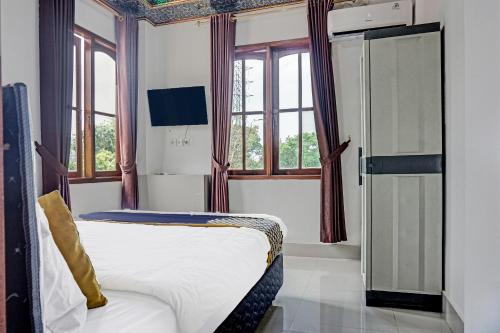 スカブミにあるSuper OYO 2226 Nurmega Jayaのベッド、窓、冷蔵庫が備わる客室です。
