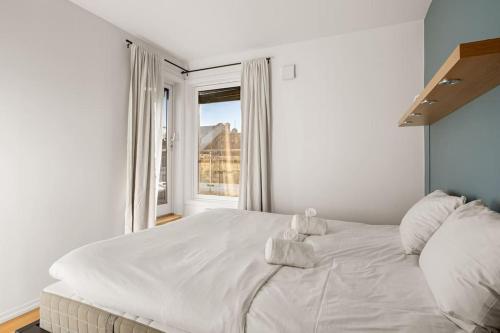 białe łóżko w pokoju z oknem w obiekcie Dinbnb Apartments I Panoramic Rooftop I 700m to Oslo Central Station w Oslo