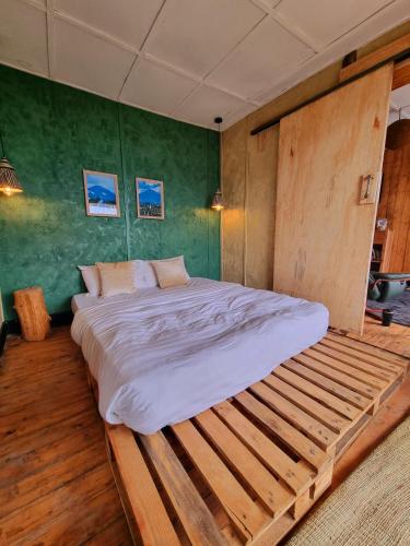 a large wooden bed in a bedroom with green walls at Khaya Nzuri 