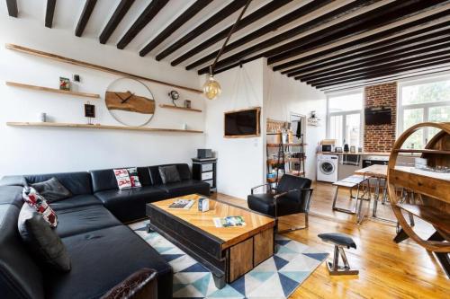ein Wohnzimmer mit einem schwarzen Sofa und einem Tisch in der Unterkunft Vieux Lille triplex de 100 m2 in Lille