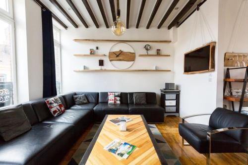 ein Wohnzimmer mit einem schwarzen Ledersofa und einem Tisch in der Unterkunft Vieux Lille triplex de 100 m2 in Lille