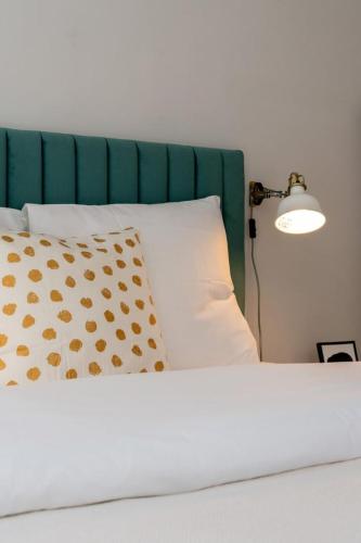 - un lit avec une tête de lit verte, un oreiller et une lampe dans l'établissement Lille Hypercentre/Train station-Superb studio, à Lille