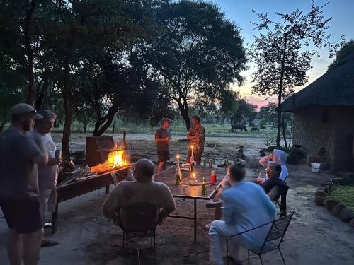 eine Gruppe von Menschen, die an einem Tisch mit einem Feuer sitzen in der Unterkunft Sukulu Reserve in Livingstone