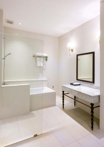 a bathroom with a tub and a sink and a mirror at Le Thatluang D'oR Boutique Hotel in Vientiane