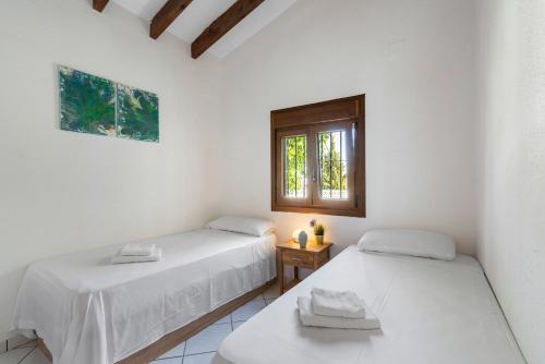 two beds in a white room with a window at Villa Maeva - PlusHolidays in Casas de Torrat