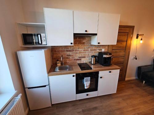 a small kitchen with white cabinets and a sink at Main Street Apartments in Sopot
