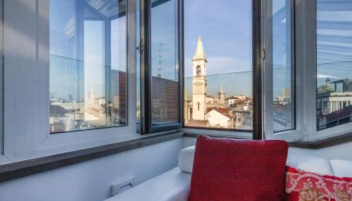 a room with windows with a red chair and a clock tower at Italianway Comfort - Torino 57 B in Milan