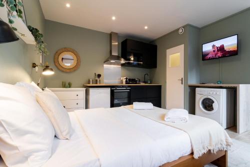 Cet appartement comprend une chambre avec un lit blanc et une cuisine. dans l'établissement Hypercentre-gares: superbe studio équipé, à Lille