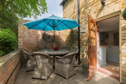 a table and chairs with an umbrella on a patio at Piglet Lodge in Pebworth