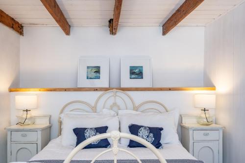 a bedroom with a white bed with blue pillows at Sea Horses in Port Isaac