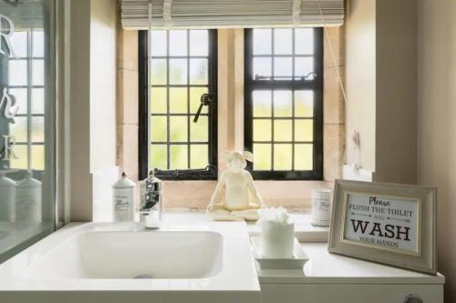 um balcão de casa de banho com um lavatório e uma janela em Piglet Lodge em Pebworth