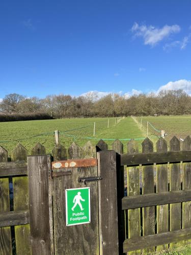 a sign on a wooden fence with a field behind it at Priors Oak - A Cosy Studio with Countryside Views in Dorset in Stalbridge