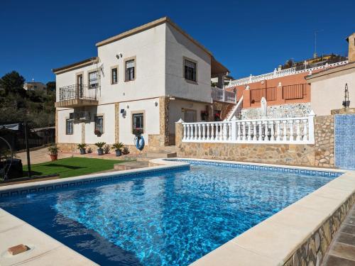 a villa with a swimming pool in front of a house at Buen Estar, piscina, barbacoa, jacuzzi en Valencia in Turís