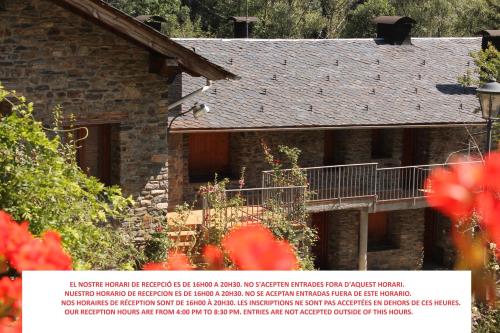 a stone house with a balcony and red flowers at Apartaments Turístics Vilaró in Llorts