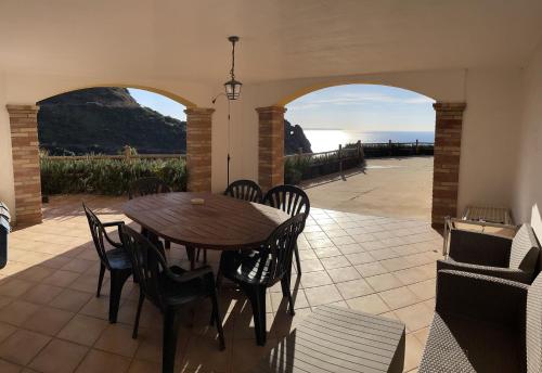 a table and chairs on a patio with a view of the ocean at Il Sole ed Il Mare Tanca Piras in Nebida